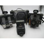 A collection of vintage cameras including two Polaroids, a Zenit- and a No. 3-A Folding Brownie.