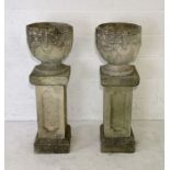 A pair of concrete garden urns with Grecian design on sectional plinths overall height 110cm