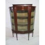 An Edwardian inlaid serpentine fronted display cabinet with Harrods Ltd label to reverse