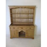 A pine dresser with three drawers, two cupboards and dog kennel opening