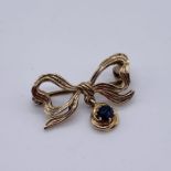 A 9ct gold brooch in the form of a bow with a sapphire drop underneath, total weight 3.1g