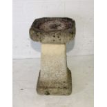 A concrete bird bath on tapered plinth