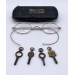 A pair of antique spectacles in case along with various watch keys