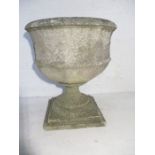 A weathered reconstituted stone garden urn