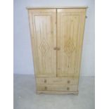 A modern pine effect wardrobe with two drawers under