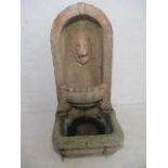 A reconstituted stone water feature with lion head mouth piece
