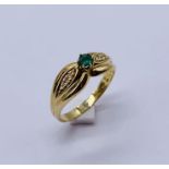 An 18ct gold ring set with an emerald and diamonds to the shoulders, weight 3.9g