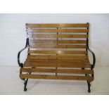 A wooden slatted garden bench with wrought iron ends