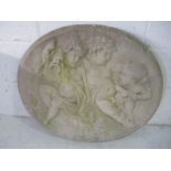 A large oval reconstituted stone plaque depicting cherubs, 68cm x 59cm approx.