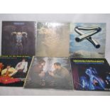 A collection of six 12" vinyl records including John Lennon, The Eagles, The Troggs, Paul Simon,