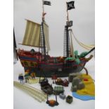 A Playmobile pirate ship with desert island, along with associated Playmobile figurines, crates,