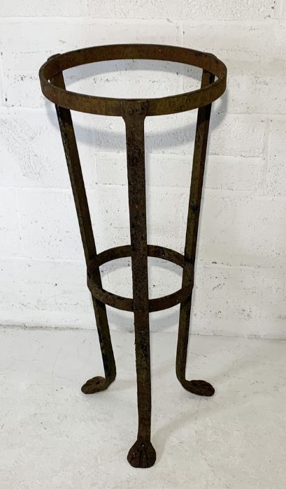 A wrought iron plant stand on tripod legs and formed feet H