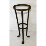 A wrought iron plant stand on tripod legs and formed feet H