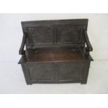 An antique oak settle with lift up seat and carved decoration