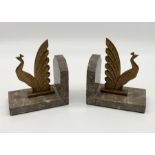 A pair of Art Deco copper patinated spelter peacock bookends on marble bases