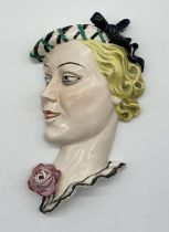 An Art Deco wall mask of a ladies head with a flower - marked to reverse F.X. 47.