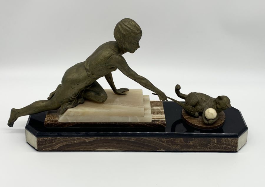 A French Art Deco gold patinated spelter figure of a girl playing with a cat holding an ivorine