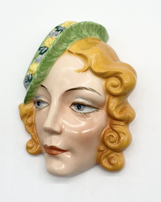 A Czechoslovakian Art Deco ceramic wall mask with green hat - numbered to the back. 18cm high.