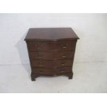 A reproduction serpentine chest of four drawers.