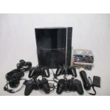 An unboxed Sony PlayStation 3 console with power cables, four controllers, eight games, motion