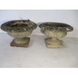 A pair of weathered reconstituted stone garden planters on plinths.