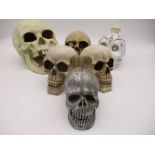 A collection of ornamental skulls including a liquor bottle, money box, bookends etc.