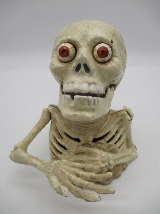 A cast iron money box in the form of a skeleton