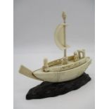 A late 19th Century Chinese ivory sailing boat with three figures aboard, on carved wooden base,