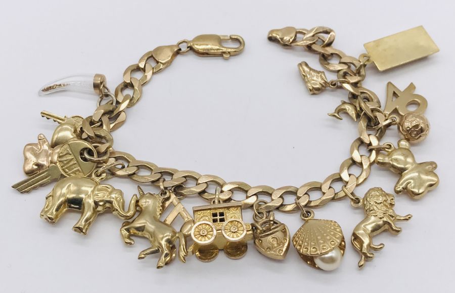 A 9ct gold charm bracelet with various novelty charms including a gypsy caravan which opens to