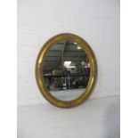 A gilt framed oval mirror.