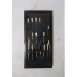 A small display case, containing a quantity of sewing hooks.