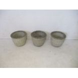 Three matching concrete garden planters.