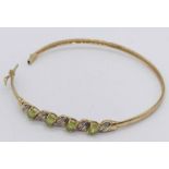 A 9ct gold (unmarked) bangle set with peridot and diamonds, weight 5.1g