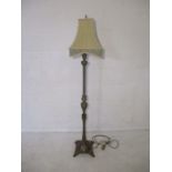 A brass style floor standing lamp and shade.
