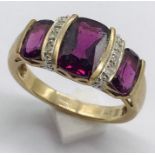 A garnet three stone ring interspersed with diamonds set in 9ct gold