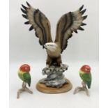 A large ceramic eagle on wooden base signed A Balarci along with two lovebirds by Goebel