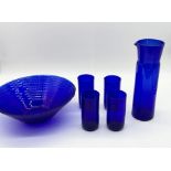 A collection of blue glass including Spiegelau jug, four beakers and a large bowl
