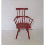 An antique Welsh comb chair, painted red, with damage to the right side of the top rail and
