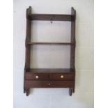 An antique wall hanging set of shelves with three drawers.