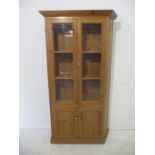 An antique pine glazed cupboard.