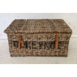 A large wicker laundry basket with leather straps