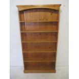 A tall freestanding pine bookcase.