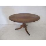 A Georgian mahogany oval tilt top dining table, on turned tripod base with original castors.