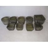 A collection of nine concrete garden planters.