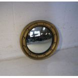 A circular gilded convex mirror.