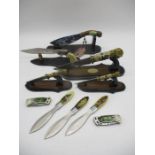 A collection of novelty knives including five displayed on stands, pocket knives and throwing