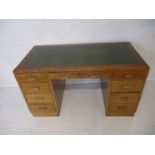 A mid century oak desk, with green leather top, length 136cm, height 76cm.