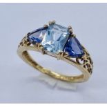 A three stone ring set with aquamarine and garnet coloured stones set in 9ct gold