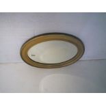 A gilt framed oval wall mirror, with bevel edge.