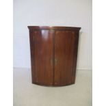 An Georgian inlaid mahogany corner cupboard, with ornate brass escutcheons.